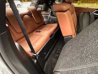 2026-Outlander-PHEV-seating - West-Central Cross Roads Cargo area of a car with orange-brown leather rear seats folded down, gray carpeting, and a visible seat belt.
